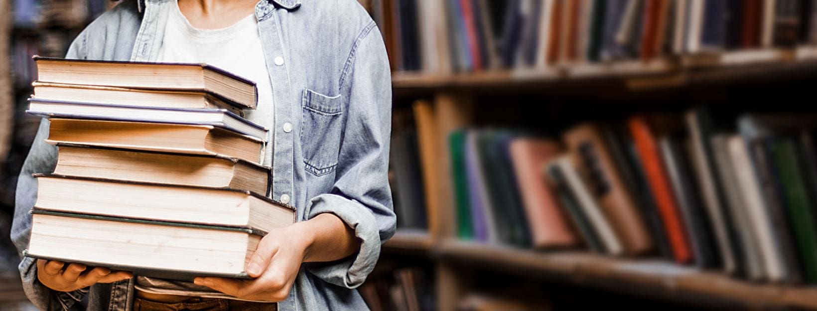 student holding books in a library